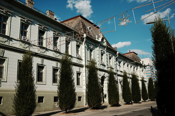 Elegant mint-green baroque-style building with trimmed trees in Zrenjanin, Serbia. Street view...