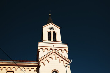 Clock tower of a historic church in Zrenjanin, Serbia, shot against deep blue sky. Minimalist...