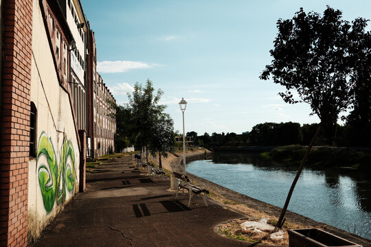 Riverside promenade with benches and trees along the old industrial buildings in Zrenjanin, Serbia.