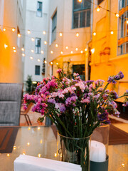 Charming outdoor cafe setting with flowers and warm lights in the evening