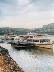 Fototapeta premium Beautiful riverboats docked along the scenic waterfront in Budapest during golden hour