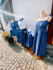 Dresses displayed on mannequins along a cobblestone street in a quaint market setting