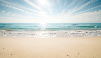 Fototapeta premium Sunlight sparkles on the gentle ocean waves as they meet the sandy shore under a bright, wispy sky