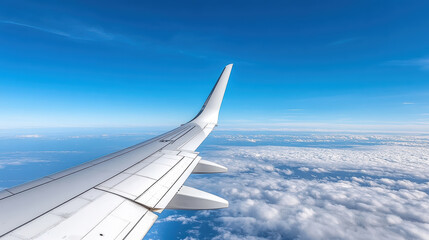 Obraz premium Aerial view of airplane wing above clouds and blue sky, creating serene travel experience