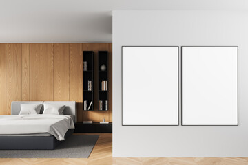 Modern bedroom interior with two blank poster mockups on white wall beside wooden panel backdrop...