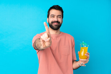 Young man over holding a cocktail over isolated blue background showing and lifting a finger