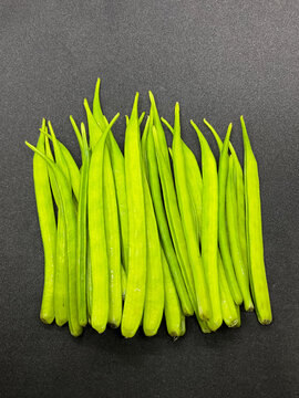 A pile of legumes, cluster beans also known as guar beans or guar pods on dark gray background 