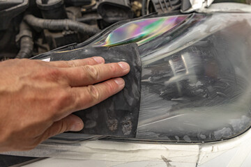 Polishing damaged car headlights with sandpaper, car lamp renovation on parking