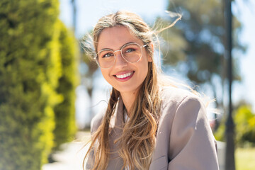 Pretty blonde Uruguayan woman with glasses at outdoors With happy expression
