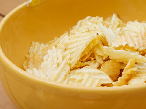 Gros plan sur un bol de chips ondul&eacute;es dans un saladier jaune lors d&rsquo;un ap&eacute;ritif en ext&eacute;rieur