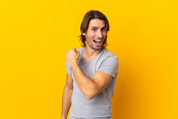 Young handsome man isolated on yellow background celebrating a victory
