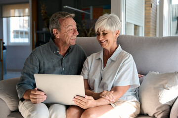 Happy senior couple using laptop at home