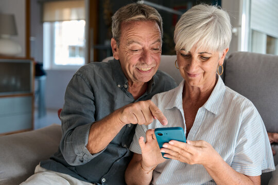 Happy senior couple using smartphone at home