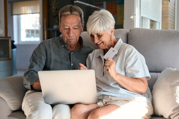 Senior couple making online payment using laptop and credit card at home