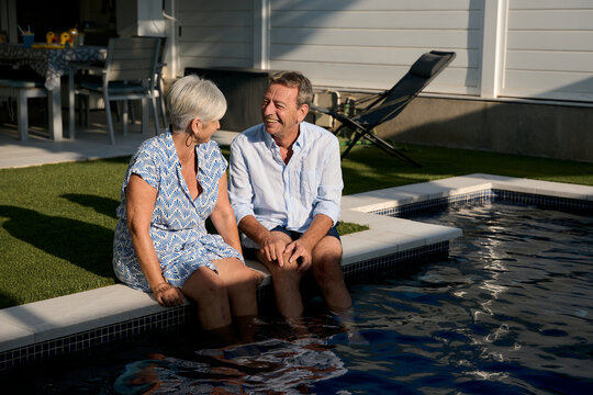 Happy senior couple relaxing by the poolside at home