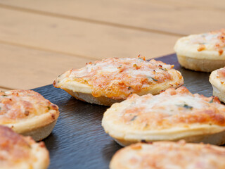 Mini pizzas apéritives disposées en rang sur une ardoise noire lors d’un buffet d’extérieur, ambiance conviviale
