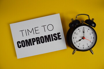 Time to Compromise alphabet letters with alarm clock flat lay on yellow background