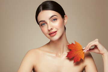 Portrait of beautiful young woman with autumn leafs. Healthy clean fresh skin natural make up beauty eyes