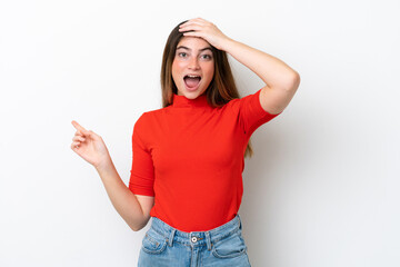 Young caucasian woman isolated on white background surprised and pointing finger to the side