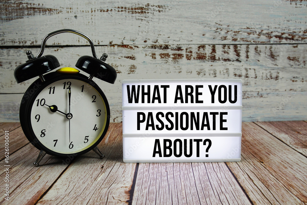 Poster what are you passionate about? text on light box with alarm clock on wooden background