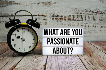 What are you Passionate About? text on light box with alarm clock on wooden background