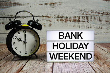 Bank Holiday Weekend text on light box with alarm clock on wooden background