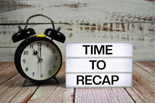 Time to Recap text on light box with alarm clock on wooden background