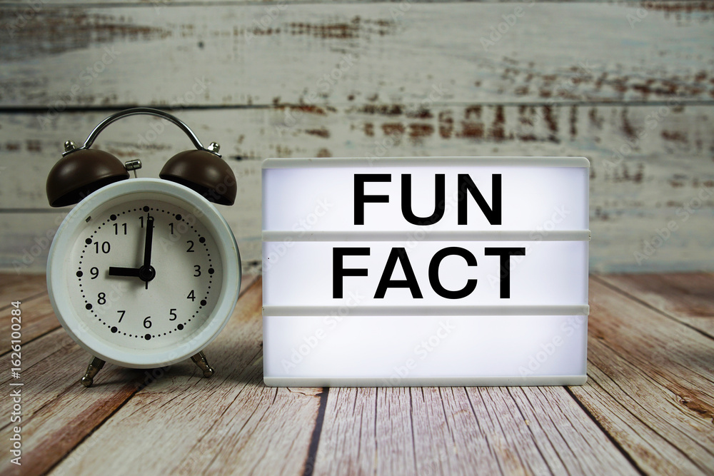 Poster fun fact text on light box with alarm clock on wooden background