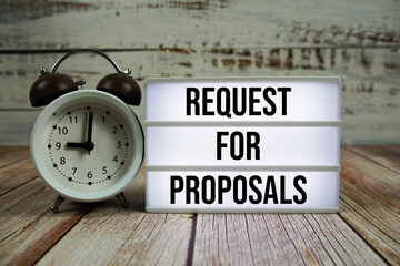 Request For Proposals text on light box with alarm clock on wooden background