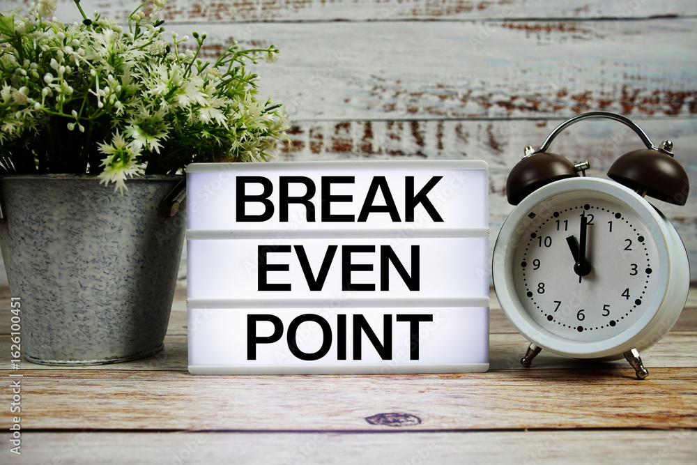 Poster break even point text on light box with alarm clock on wooden background