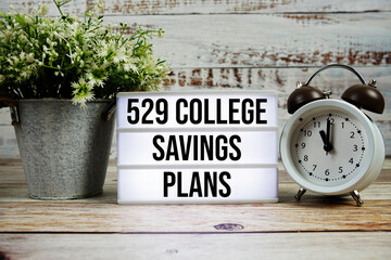 529 College Savings Plans text on light box with alarm clock on wooden background