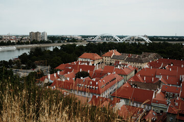 Elevated view of Novi Sad with red rooftops of Petrovaradin and modern buildings across the Danube...