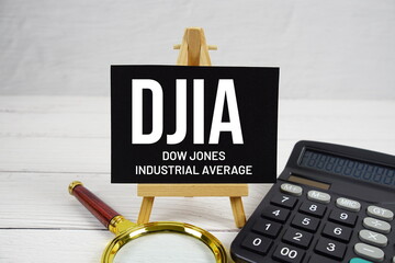 DJIA Dow Jones Industrial Average text with magnifying glass and calculator on wooden background