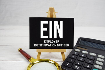 EIN Employer Identification Number text with magnifying glass and calculator on wooden background