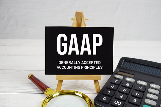 GAAP Generally Accepted Accounting Principles text with magnifying glass and calculator on wooden background