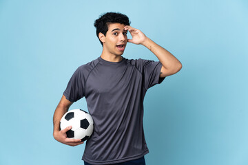 Venezuelan football player man over isolated background doing surprise gesture while looking to the...