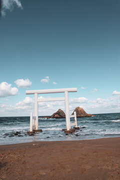 White Torii Gate Standing in the Sea at Futamigaura, Itoshima, Japan Under Blue Sky