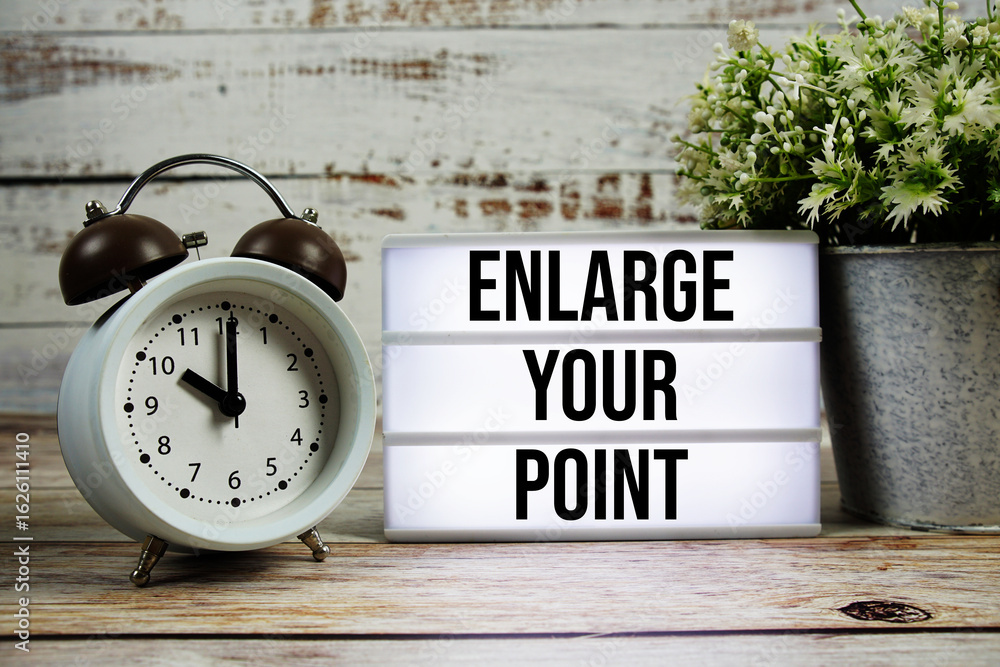 Poster enlarge your point text on light box with alarm clock on wooden background