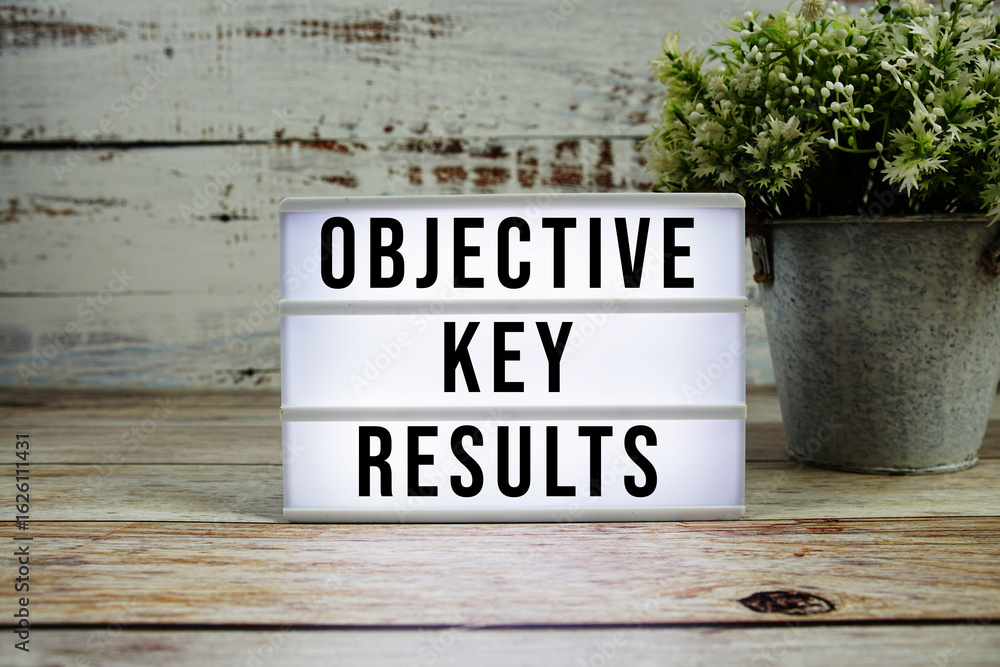 Poster objective key results text on light box with alarm clock on wooden background