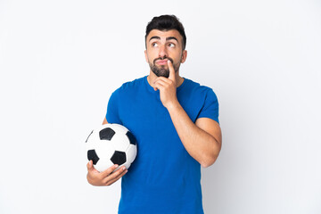 Handsome young football player man over isolated wall having doubts while looking up