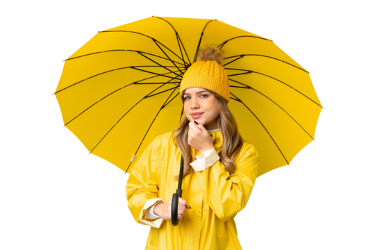 Young girl with rainproof coat and umbrella over isolated chroma key background and looking up