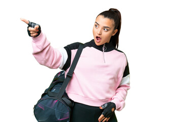 Young sport woman with sport bag over isolated chroma key background pointing away
