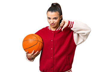 Young Woman playing basketball over isolated chroma key background showing thumb down with negative...