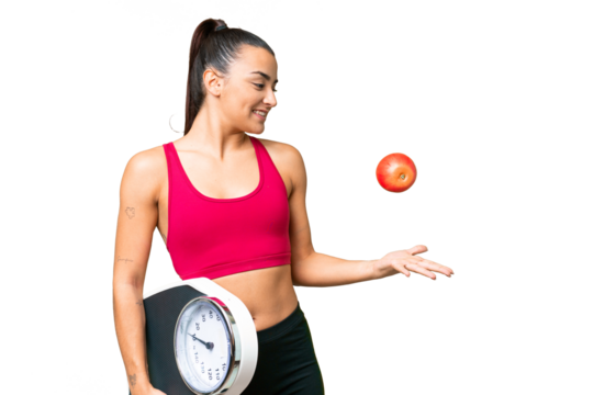 Young beauty woman over isolated chroma key background with weighing machine and with an apple