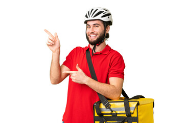 Young delivery man with thermal backpack over isolated chroma key background pointing finger to the side and presenting a product