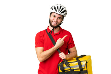 Young delivery man with thermal backpack over isolated chroma key background pointing to the side...