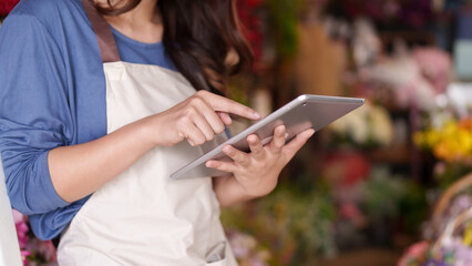 Asian adult hands manage floral shop business using digital tablet for efficient operations and...