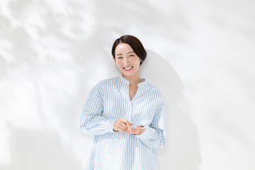 木漏れ日の中に立つ笑顔の女性