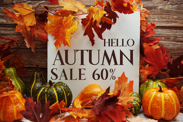 Hello Autumn Sale 60% text with maple leaf decoration on wooden background