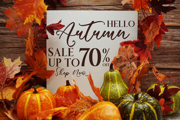 Hello Autumn Sale 70% text with maple leaf decoration on wooden background